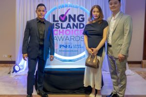 Three adults in formal attire pose in front of a Long Island Choice Awards backdrop with blue lighting and a circular logo.