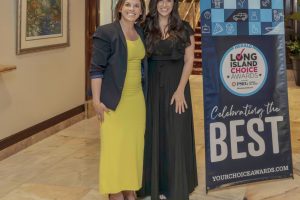 Two smiling women in formal dresses pose together at an awards event beside a blue Long Island Choice Awards banner that reads 'BEST'.