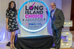 Two people pose beside a blue neon ring that reads 'Long Island Choice Awards' presented by PSEG Long Island.