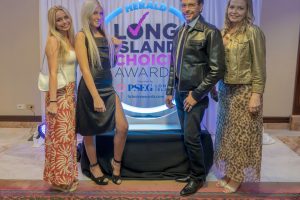 Four adults posing in front of a Herald Long Island Choice Awards backdrop, smiling at the camera.