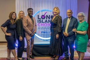 Six well-dressed individuals posing on a red carpet in front of a Herald Long Island Choice Awards backdrop.