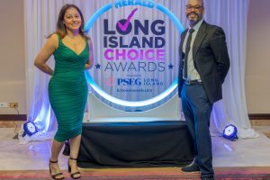 Two guests pose at an awards event in front of a glowing circular 'Herald Long Island Choice Awards' backdrop.