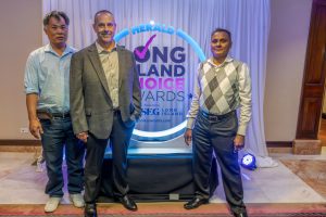 Three men pose for a photo on a stage in front of a 'Herald Long Island Choice Awards' backdrop at an awards event.