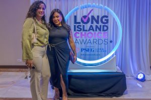 Two women pose together at an awards event in front of a neon-blue circular backdrop reading 'Long Island Choice Awards'.