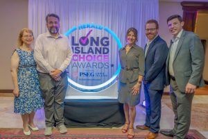 Five people in smart casual attire pose for a photo in front of a neon-lit ‘Long Island Choice Awards’ backdrop.