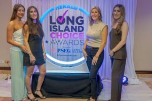 Four women posing in front of a neon-lit 'Long Island Choice Awards' backdrop at an indoor event.